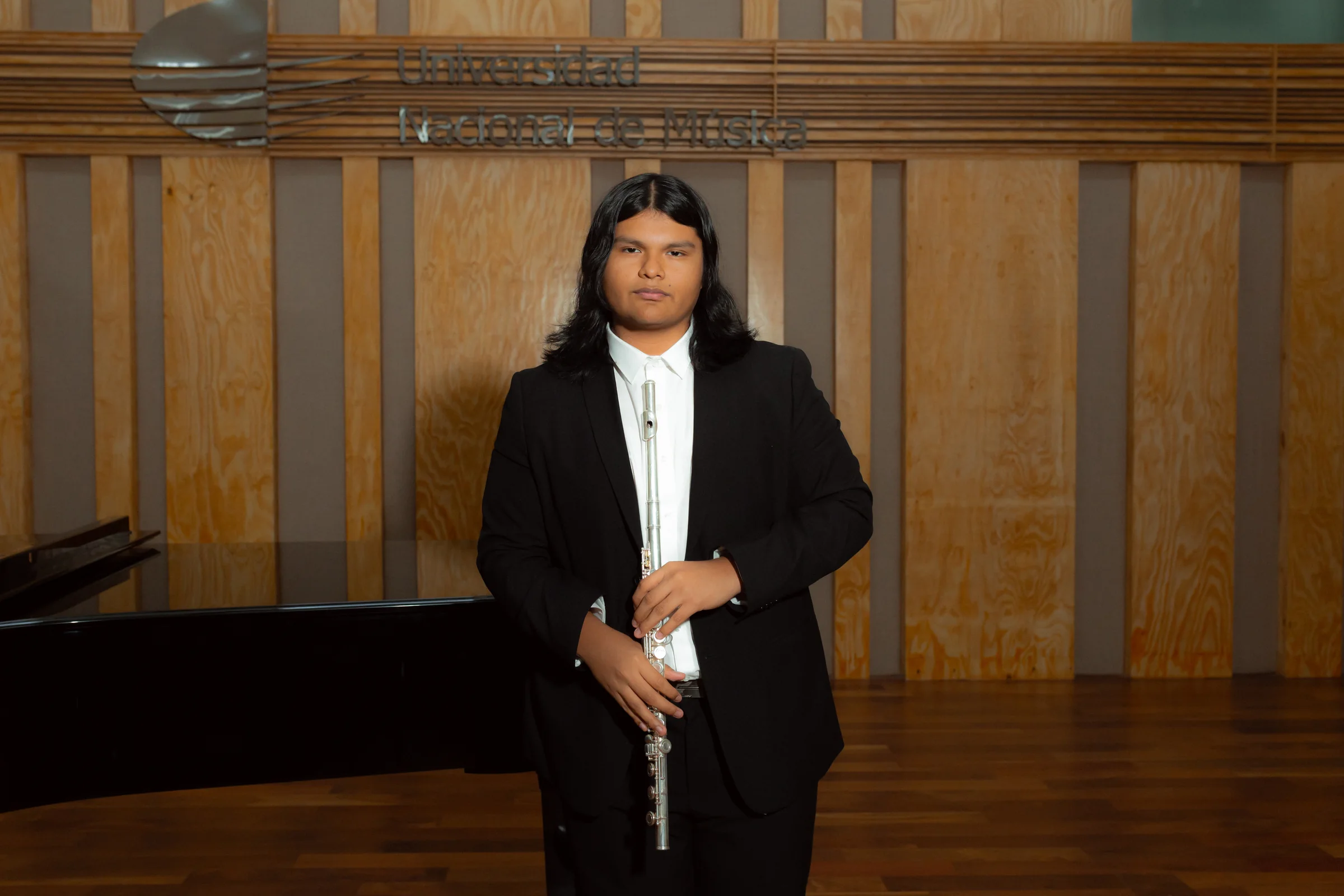 Adrián Cruz junto a un piano de cola con su flauta